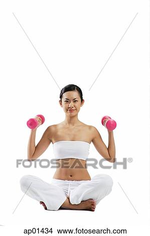 Woman sitting crossed legged on floor, lifting dumbbells View Large Photo Image Picture - Woman sitting crossed legged on floor, lifting dumbbells. Fotosearch