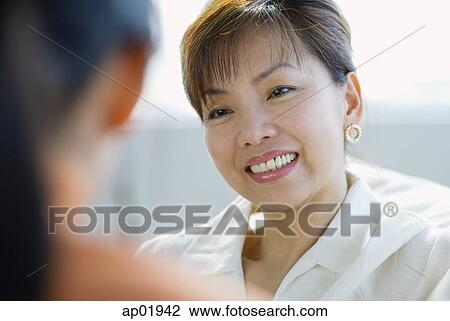 Stock Image - Woman smiling, focus on the background. Fotosearch