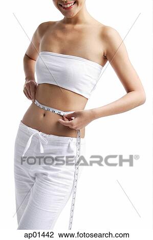 Woman standing, holding tape measure around waist View Large Photo Image Stock Image - Woman standing, holding tape measure around waist. Fotosearch