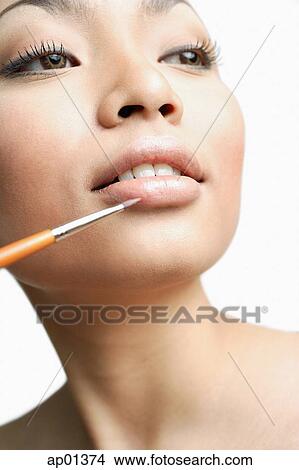 Woman using lipstick brush, portrait View Large Photo Image Picture - Woman using lipstick brush, portrait. Fotosearch