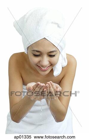Stock Photography - Woman washing her face, cupping water in hand. Fotosearch