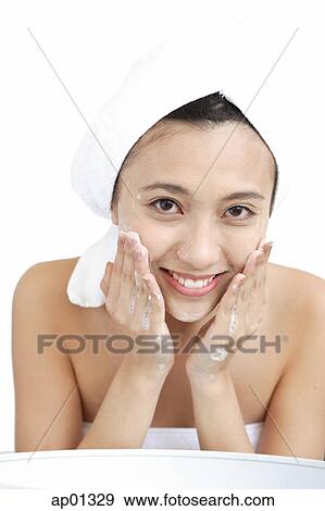 Stock Photo - Woman washing her face, looking at camera. Fotosearch
