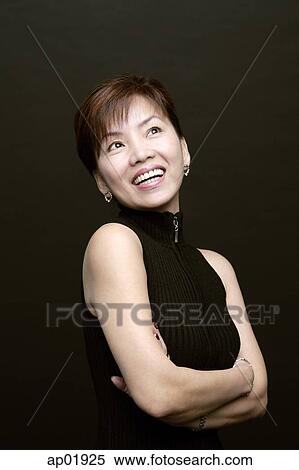 Stock Photography - Woman with arms crossed, smiling, looking up. Fotosearch