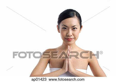 Stock Image - Woman with hands together, looking at camera. Fotosearch