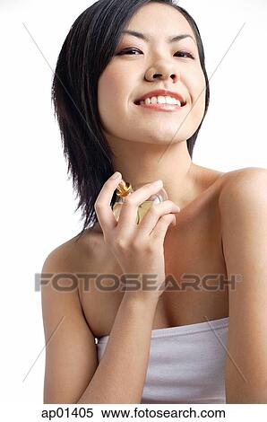 Stock Photography - Woman with perfume bottle, looking at camera, smiling. Fotosearch