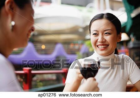 Stock Photograph - Women holding glasses of wine, toasting. Fotosearch