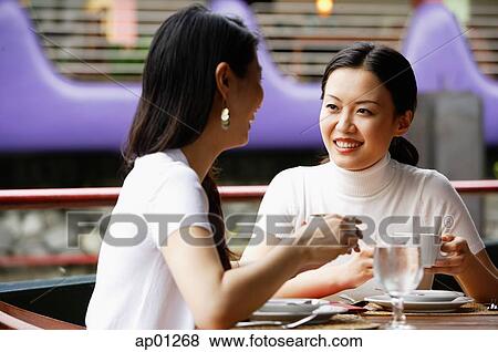 Women in cafe, drinks in hand, sitting at table View Large Photo Image Stock Photo - Women in cafe, drinks in hand, sitting at table. Fotosearch