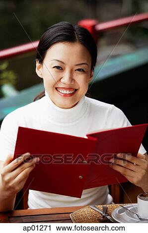 Women in cafe, holding menu, smiling at camera View Large Photo Image Stock Image - Women in cafe, holding menu, smiling at camera. Fotosearch