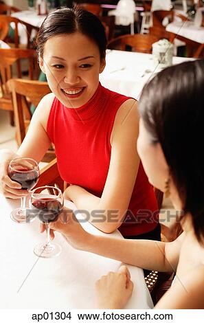 Picture - Women in restaurant, holding wine glasses. Fotosearch