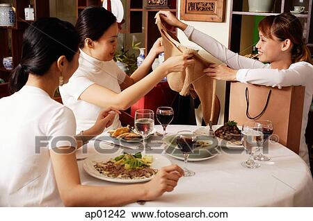 Women in restaurant, one woman showing clothing item to the others View Large Photo Image Stock Image - Women in restaurant, one woman showing clothing item to the others. Fotosearch