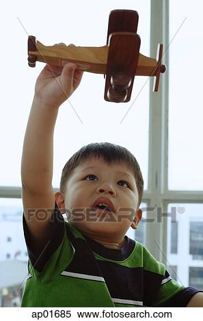 Young boy holding toy airplane, looking up View Large Photo Image Stock Photography - Young boy holding toy airplane, looking up. Fotosearch