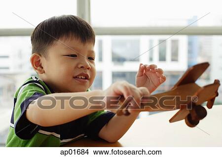 Picture - Young boy holding toy airplane. Fotosearch