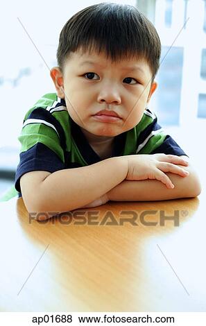 Young boy looking away, arms crossed, leaning on table View Large Photo Image Stock Photo - Young boy looking away, arms crossed, leaning on table. Fotosearch
