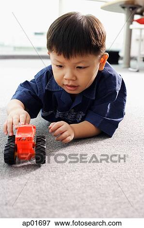 Young boy lying on floor, playing with toy tractor View Large Photo Image Stock Photo - Young boy lying on floor, playing with toy tractor. Fotosearch
