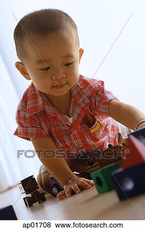 Young boy on floor, playing with toy train View Large Photo Image Stock Photo - Young boy on floor, playing with toy train. Fotosearch