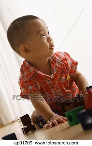 Young boy on floor, playing with toys, looking away View Large Photo Image Stock Photo - Young boy on floor, playing with toys, looking away. Fotosearch