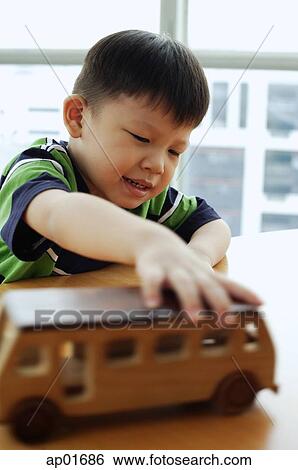 Young boy playing with toy bus View Large Photo Image Stock Photograph - Young boy playing with toy bus. Fotosearch