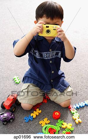 Young boy playing with toy camera, holding in front of his face View Large Photo Image Stock Photograph - Young boy playing with toy camera, holding in front of his face. Fotosearch
