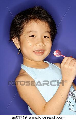 Stock Photo - Young girl holding lollypop, smiling. Fotosearch