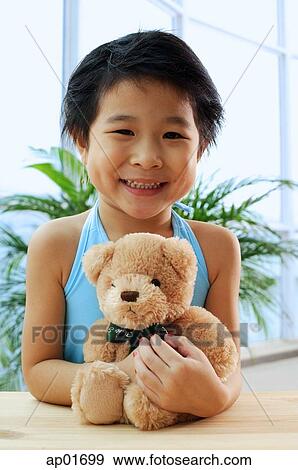 Young girl holding teddy bear, smiling at camera View Large Photo Image Stock Photo - Young girl holding teddy bear, smiling at camera. Fotosearch