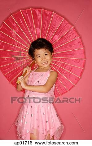 Young girl in pink dress holding red umbrella, smiling View Large Photo Image Stock Photograph - Young girl in pink dress holding red umbrella, smiling. Fotosearch
