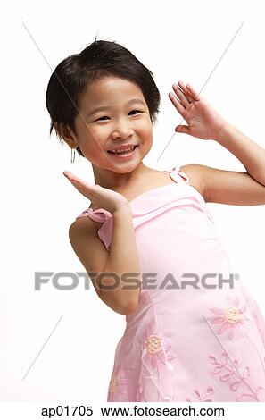 Stock Photography - Young girl in pink dress, smiling at camera, hands up. Fotosearch