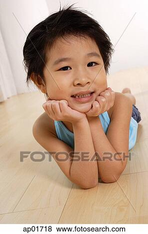 Young girl lying on floor, hands on chin View Large Photo Image Stock Photo - Young girl lying on floor, hands on chin. Fotosearch