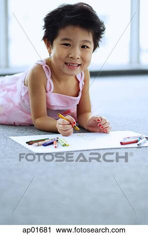 Young girl lying on floor, holding crayons, smiling at camera View Large Photo Image Stock Image - Young girl lying on floor, holding crayons, smiling at camera. Fotosearch