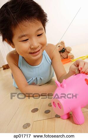 Young girl lying on floor, putting money in piggy bank View Large Photo Image Stock Photo - Young girl lying on floor, putting money in piggy bank. Fotosearch