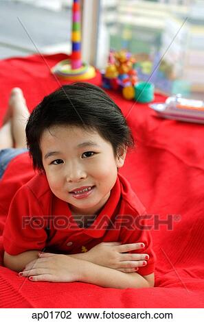 Stock Image - Young girl lying on sofa, looking at camera. Fotosearch
