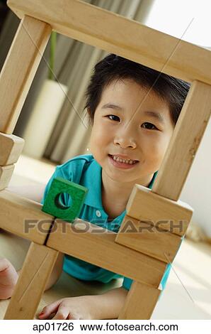 Stock Photograph - Young girl playing with building blocks, looking at camera. Fotosearch