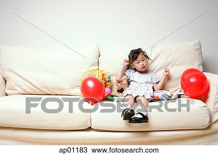 Young girl sitting on sofa, looking at camera View Large Photo Image Stock Image - Young girl sitting on sofa, looking at camera. Fotosearch