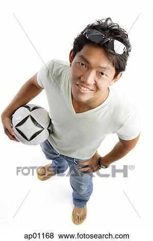Young man in T-shirt and jeans, holding soccer ball, smiling at camera, hands on hip View Large Photo Image Stock Photo - Young man in T-shirt and jeans, holding soccer ball, smiling at camera, hands on hip. Fotosearch
