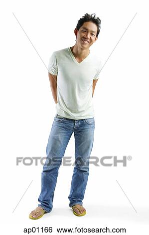Young man in T-shirt and jeans, standing, smiling at camera View Large Photo Image Stock Photograph - Young man in T-shirt and jeans, standing, smiling at camera. Fotosearch