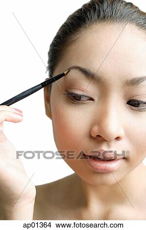 Young woman holding eyebrow pencil to eyebrow View Large Photo Image Picture - Young woman holding eyebrow pencil to eyebrow. Fotosearch