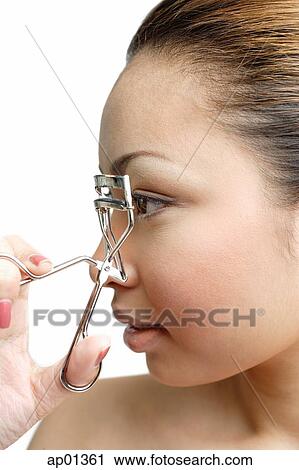 Young woman holding eyelash curler near eye, profile View Large Photo Image Stock Image - Young woman holding eyelash curler near eye, profile. Fotosearch