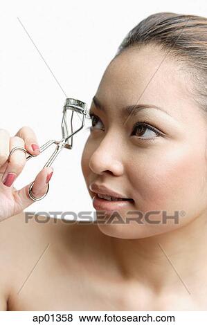 Young woman holding eyelash curler View Large Photo Image Stock Photo - Young woman holding eyelash curler. Fotosearch