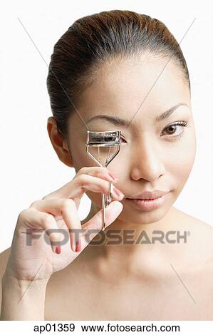 Young woman holding eyelash curler, looking at camera View Large Photo Image Stock Photo - Young woman holding eyelash curler, looking at camera. Fotosearch