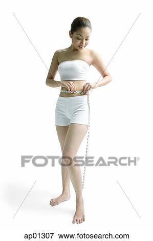 Young woman measuring her waist with tape measure View Large Photo Image Stock Photo - Young woman measuring her waist with tape measure. Fotosearch
