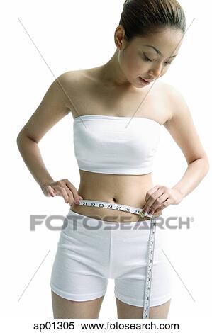 Young woman measuring her waist with measuring tape View Large Photo Image Stock Photography - Young woman measuring her waist with measuring tape. Fotosearch