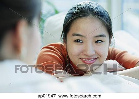 Stock Photo - Young woman smiling at person in front of her. Fotosearch