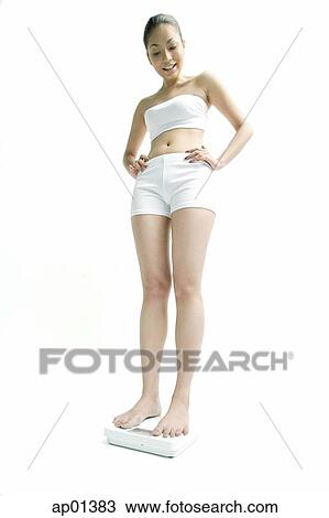 Young woman standing on weighing scale, hands on hips View Large Photo Image Stock Image - Young woman standing on weighing scale, hands on hips. Fotosearch