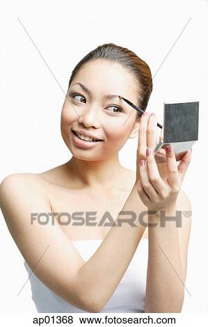 Young woman using eyebrow brush, looking away View Large Photo Image Stock Photo - Young woman using eyebrow brush, looking away. Fotosearch