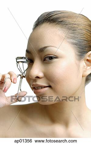 Young woman using eyelash curler, looking at camera View Large Photo Image Stock Photograph - Young woman using eyelash curler, looking at camera. Fotosearch
