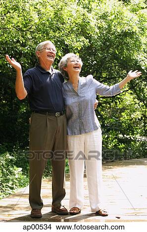 Senior couple looking up, hands outstretched View Large Photo Image Stock Photo - Senior couple looking up, hands outstretched. Fotosearch - Search Stock Images, Mural Photographs, Pictures, and Clipart Photos