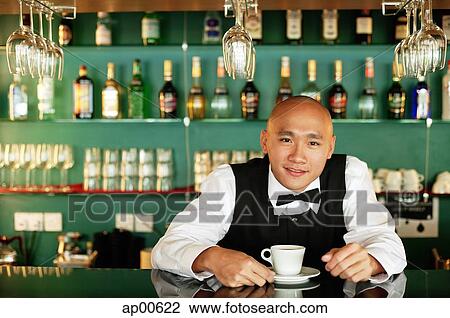 Stock Image - Bartender behind bar counter, with cup and saucer. Fotosearch