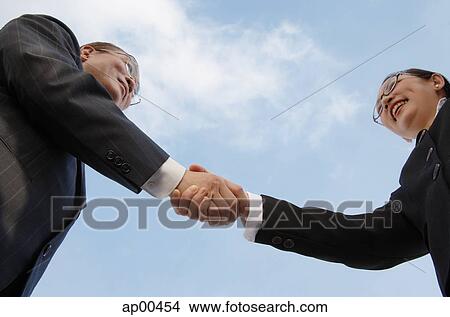 Businessman and businesswoman shaking hands, low angle view View Large Photo Image Picture - Businessman and businesswoman shaking hands, low angle view. Fotosearch