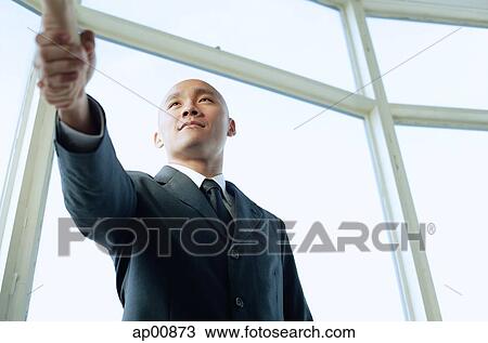 Stock Image - Businessman shaking hands with someone, low angle view. Fotosearch