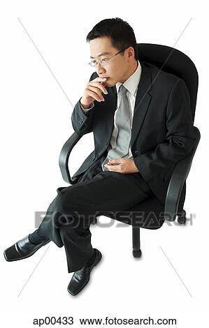 Stock Image - Businessman sitting on office chair, hand on chin. Fotosearch