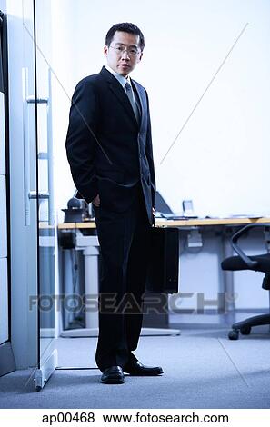 Stock Photo - Businessman standing, looking at camera, portrait. Fotosearch
